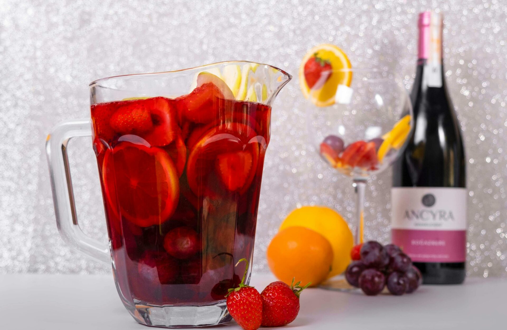 Vibrant sangria filled with fruits beside a wine bottle and glass, perfect for summer parties.