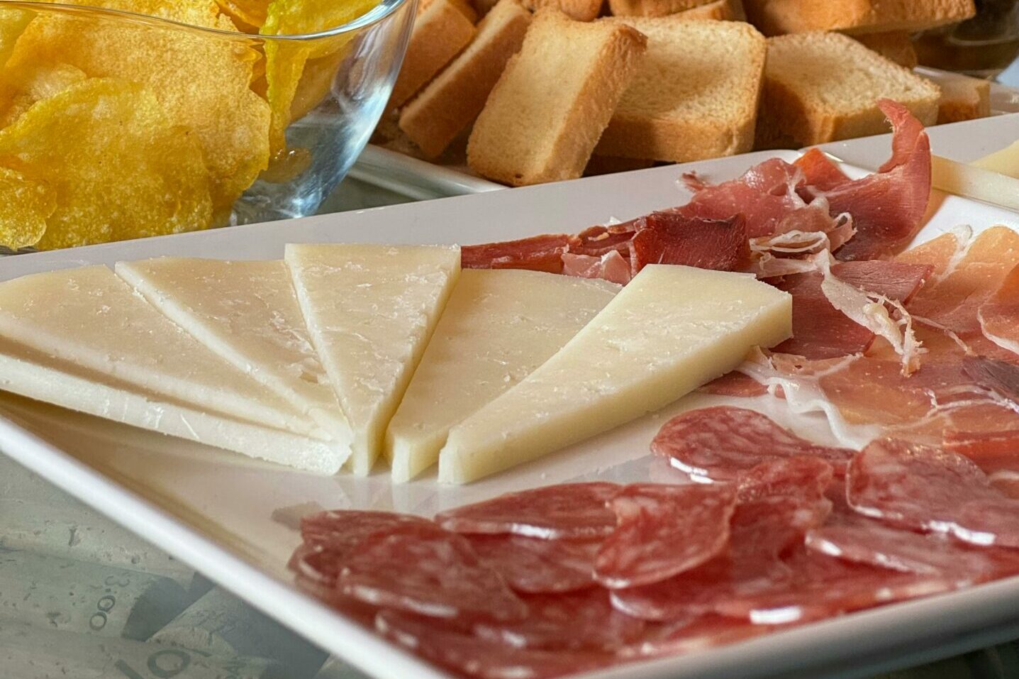 A delicious spread of Spanish tapas featuring cheese, cured meats, bread, and chips, ideal for wine tasting.